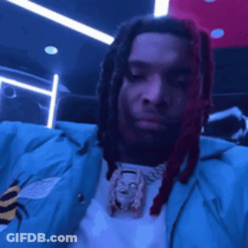 A Man With Dreadlocks Is Wearing A Blue Jacket . GIF