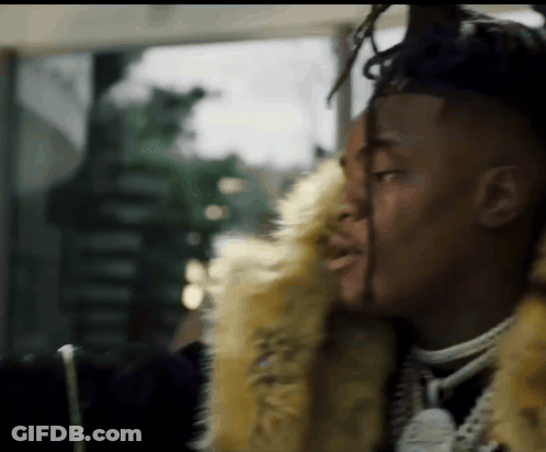 A Man With Dreadlocks Is Wearing A Fur Coat And Necklace . GIF