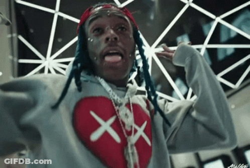 A Man With Dreadlocks Is Wearing A Grey Sweater With A Red Heart On It GIF