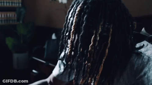 A Man With Dreadlocks Is Wearing A Shirt That Says Dior On It GIF