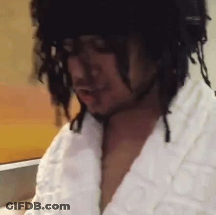 A Man With Dreadlocks Is Wearing A White Robe And A Black Hat . GIF