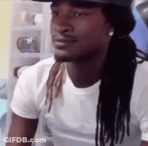 A Man With Dreadlocks Is Wearing A White Shirt And A Black Hat . GIF