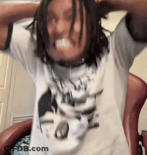 A Man With Dreadlocks Is Wearing A White Shirt With A Picture Of A Man 'S Face On It GIF