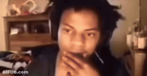 A Man With Dreadlocks Is Wearing Headphones And Covering His Mouth With His Hands . GIF