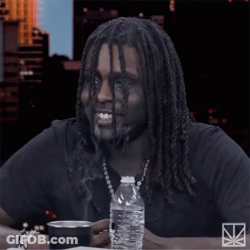 A Man With Dreadlocks Sits At A Table With A Bottle Of Water And A Cup GIF