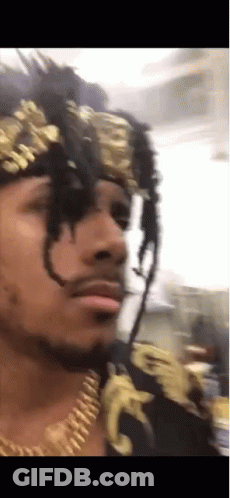 A Man With Dreadlocks Wearing A Gold Headband And Necklace GIF