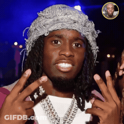 A Man With Dreadlocks Wearing A Hat And A Necklace Is Giving A Peace Sign GIF