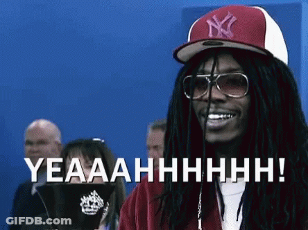 A Man With Dreadlocks Wearing A Ny Hat And Sunglasses Is Smiling And Says Yeaaahhhh ! GIF