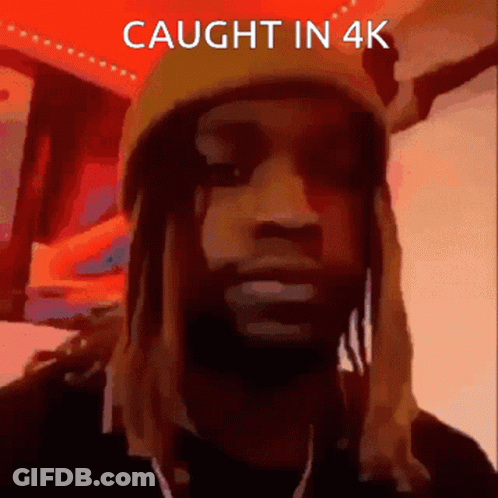 A Man With Dreadlocks Wearing A Yellow Hat With The Words Caught In 4K Below Him GIF