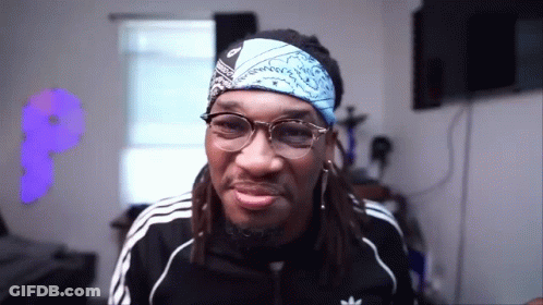 A Man With Dreadlocks Wearing Glasses And A Bandana On His Head . GIF