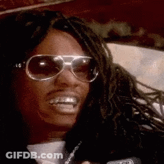 A Man With Dreadlocks Wearing Sunglasses And A Microphone Says How 'S GIF