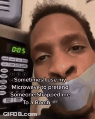 A Man With Duct Tape Around His Mouth Is Standing In Front Of A Microwave With The Time Of 0:05 GIF