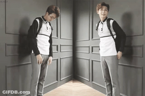 A Man With Glasses And A Backpack Is Standing In A Corner GIF