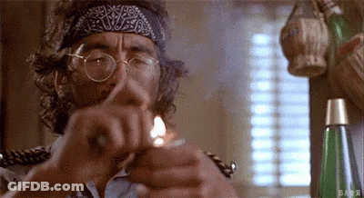 A Man With Glasses And A Bandana On His Head Is Lighting A Cigarette With A Lighter . GIF