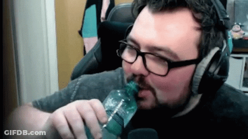 A Man With Glasses And A Beard Is Drinking From A Bottle . GIF