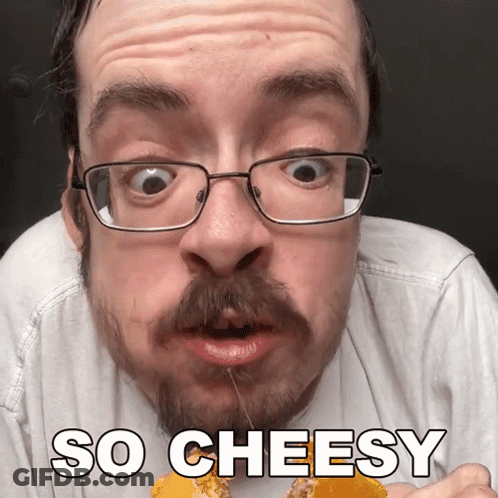 A Man With Glasses And A Beard Is Eating Cheese With The Words So Cheesy Above Him GIF