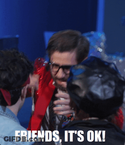 A Man With Glasses And A Beard Is Holding A Necklace With The Words Friends It 'S Ok On The Bottom GIF