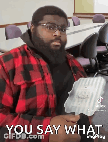 A Man With Glasses And A Beard Is Holding A Piece Of Paper That Says " You Say What " GIF