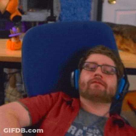 A Man With Glasses And A Beard Is Laying In A Chair With His Arm Up In The Air GIF