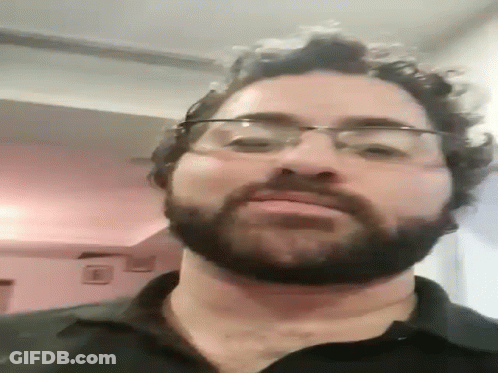 A Man With Glasses And A Beard Is Looking At The Camera . GIF