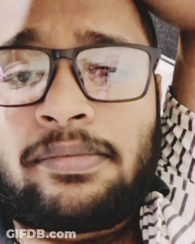 A Man With Glasses And A Beard Is Looking At The Camera GIF