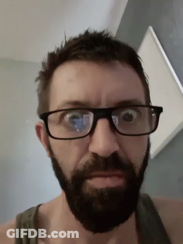 A Man With Glasses And A Beard Is Looking Down GIF