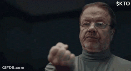 A Man With Glasses And A Beard Is Making A Funny Face With His Fist In The Air . GIF