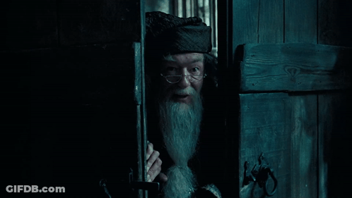 A Man With Glasses And A Beard Is Peeking Out Of A Doorway GIF