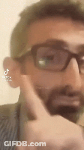 A Man With Glasses And A Beard Is Pointing His Finger At Something . GIF
