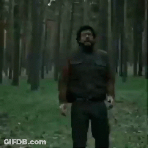 A Man With Glasses And A Beard Is Screaming In A Field . GIF