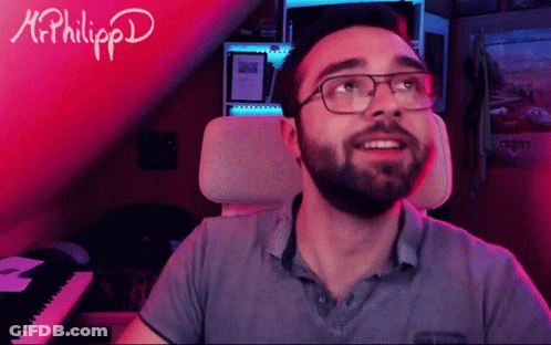 A Man With Glasses And A Beard Is Sitting In Front Of A Keyboard With The Name Mr. Philippd Written On It GIF