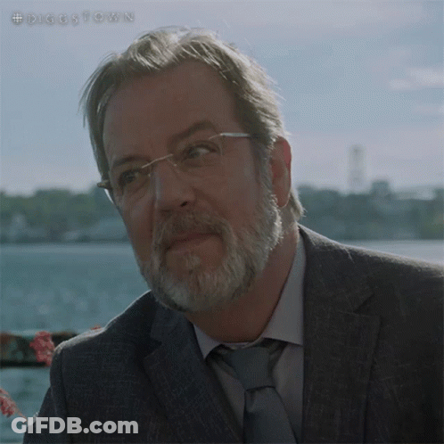 A Man With Glasses And A Beard Is Standing In Front Of A Body Of Water With The Hashtag #Diggstown GIF