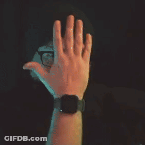 A Man With Glasses And A Beard Is Wearing A Beanie And Covering His Mouth With His Hand . GIF