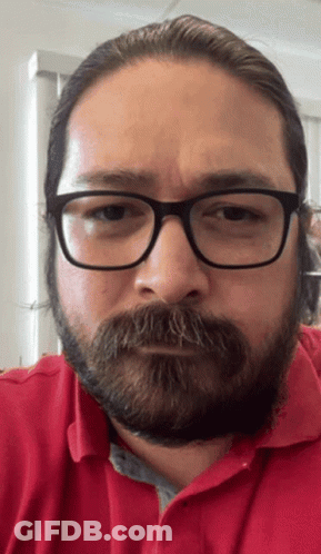 A Man With Glasses And A Beard Is Wearing A Red Polo Shirt GIF
