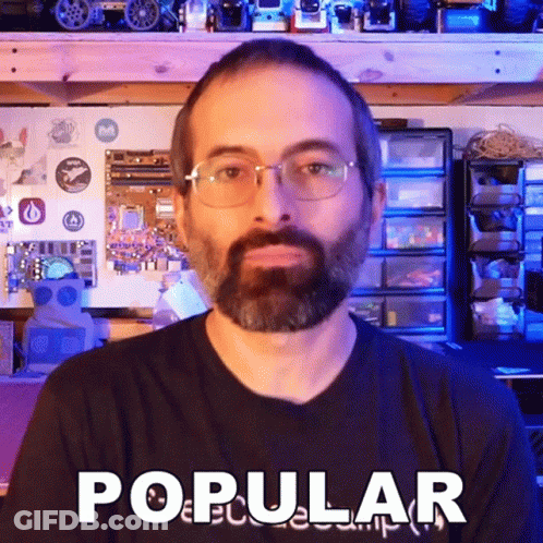 A Man With Glasses And A Beard Is Wearing A Shirt That Says Popular GIF