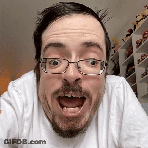 A Man With Glasses And A Beard Makes A Surprised Face GIF