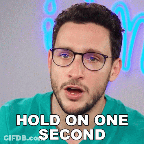 A Man With Glasses And A Beard Says " Hold On One Second " GIF