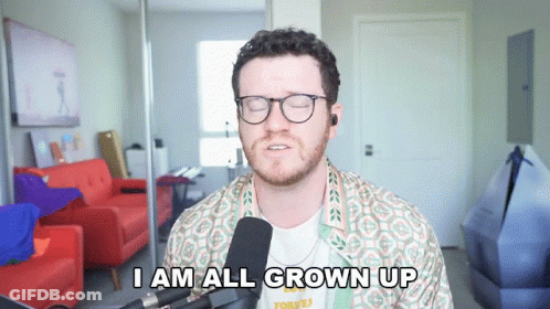 A Man With Glasses And A Beard Says I Am All Grown Up In Front Of A Microphone GIF