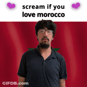 A Man With Glasses And A Beard Stands In Front Of A Morocco Flag And Says Scream If You Love Morocco GIF