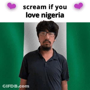 A Man With Glasses And A Beard Stands In Front Of A Nigerian Flag GIF