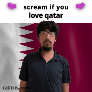 A Man With Glasses And A Beard Stands In Front Of A Qatar Flag GIF