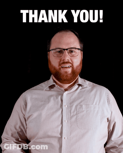 A Man With Glasses And A Beard Stands In Front Of A Sign That Says Thank You GIF
