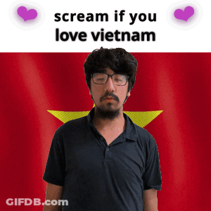 A Man With Glasses And A Beard Stands In Front Of A Vietnam Flag GIF