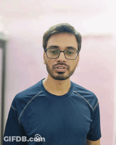 A Man With Glasses And A Beard Wears A Blue Shirt With The Letter Q On The Front GIF
