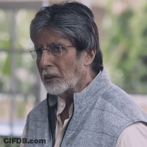 A Man With Glasses And A Beard Wears A Gray Vest GIF