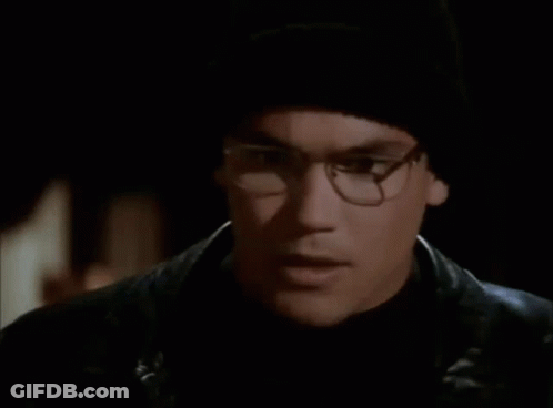 A Man With Glasses And A Black Hat Is Holding A Blue Object In Front Of His Face GIF