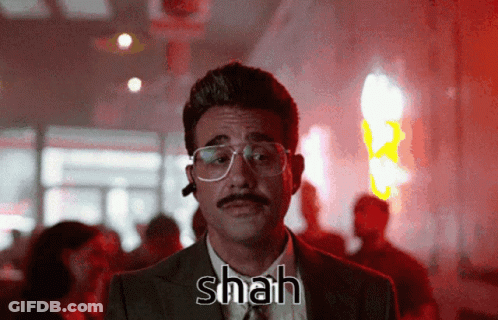 A Man With Glasses And A Mustache Has Shah Written On His Chest GIF