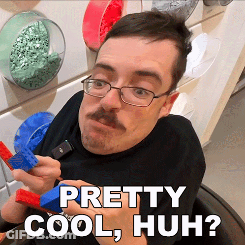 A Man With Glasses And A Mustache Is Holding A Blue And Red Lego Piece And Says Pretty Cool Huh GIF