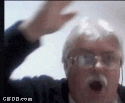 A Man With Glasses And A Mustache Is Making A Funny Face With His Hand In The Air . GIF