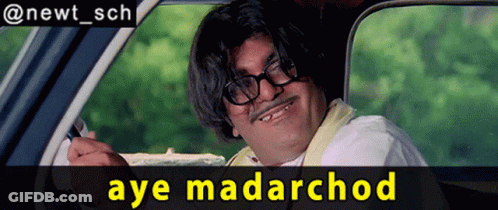 A Man With Glasses And A Mustache Is Sitting In A Car With The Words Aye Madarchod Below Him GIF